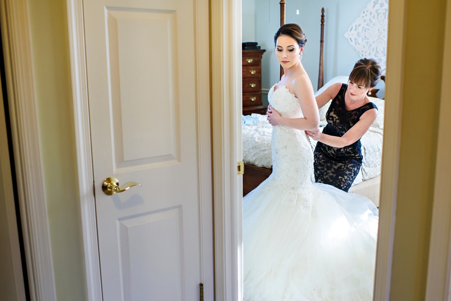 The Mother of the Bride helps her daughter put on her wedding dress.